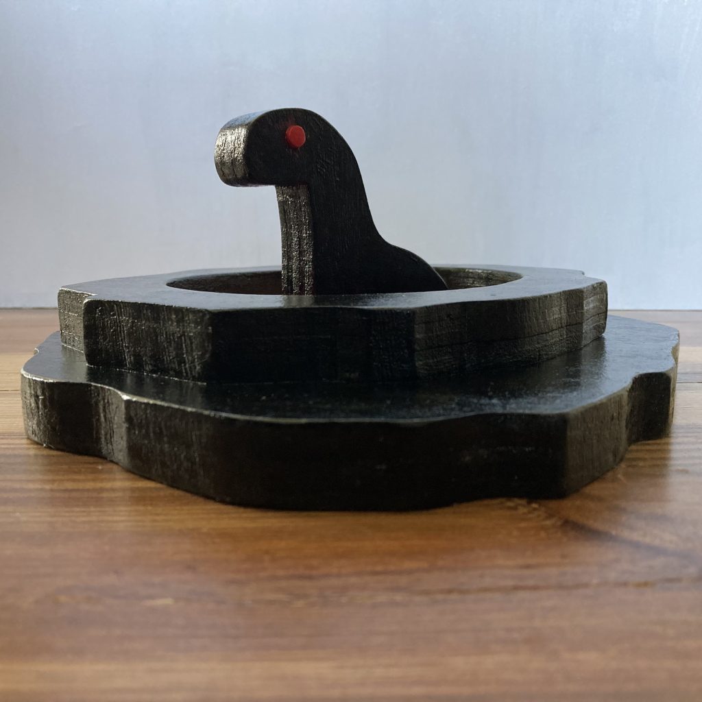 painted wooden sculpture of a creature sitting in a pool